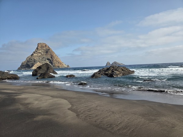 Primer plano del gran roque frente a la orilla de Playa de Las Breñas, resaltado sobre el mar.