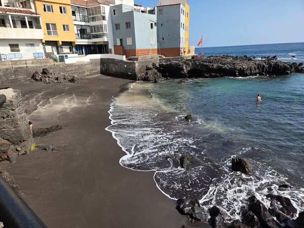 Pequeña cala protegida junto a las viviendas de colores en la punta norte de la playa, ideal para darse un baño tranquilo.