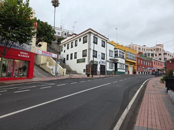 Calle principal de Tacoronte con edificios históricos de varios colores y aceras anchas en una pendiente suave.