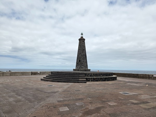 Faro-monumento de piedra en el extremo del espigón de Bajamar, frente al Atlántico.