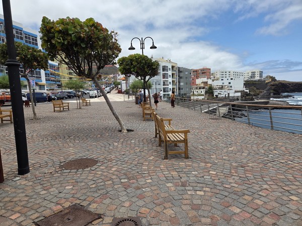 Bancos, arbolado y farolas en el paseo marítimo de Bajamar frente al océano.