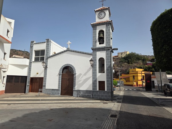 Iglesia de Barranco Hondo con torre de reloj y campana en la plaza principal.