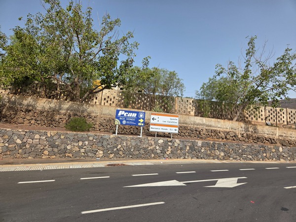 Señales direccionales del Camino Viejo de Candelaria junto a un muro de piedra, con distancias hacia la Ermita del Rosario y La Laguna.