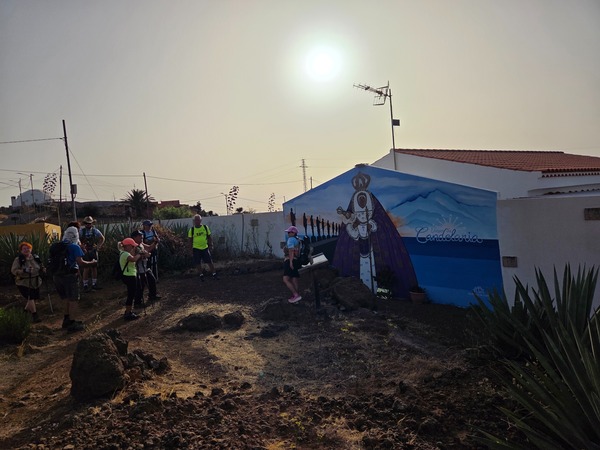 Grupo de caminantes del Camino Viejo de Candelaria junto a un mural de la Virgen con el Teide sugerido al fondo.