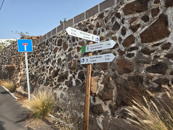 Poste de madera con flechas del Camino Viejo de Candelaria indicando la Ermita de Machado, La Laguna y la Ermita del Rosario.