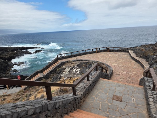 Escaleras y plataforma mirador de piedra sobre las rocas frente al mar.
