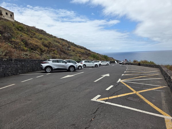 Aparcamiento asfaltado en la parte alta del acantilado con vistas al mar.
