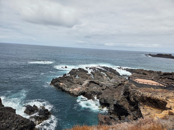 Piscinas naturales entre lavas y charcos donde algunos bañistas toman el sol.