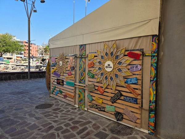 Mural decorativo con frases y símbolo solar en una terraza de El Médano.