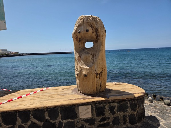 Escultura de madera con forma abstracta en la costa de El Médano frente al Atlántico.