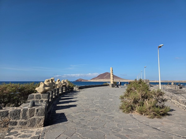 Vista panorámica del paseo marítimo de El Médano con Montaña Roja al fondo en un día despejado.