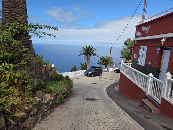 Calle empinada que baja hacia el mar entre viviendas y palmeras en El Sauzal.