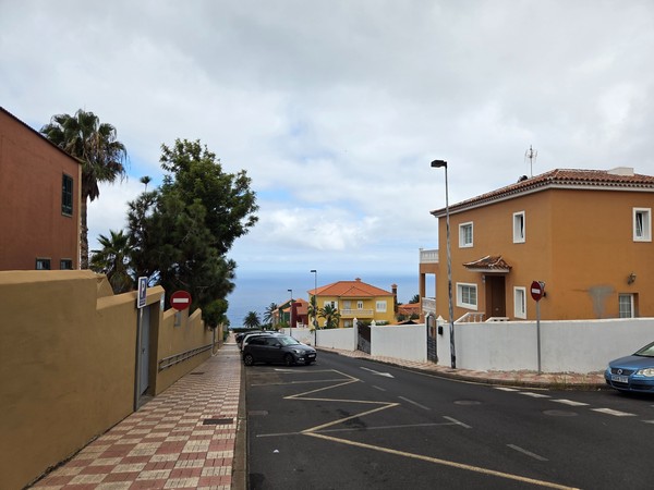 Tramo de calle con aceras amplias y casas color tierra mirando al Atlántico.