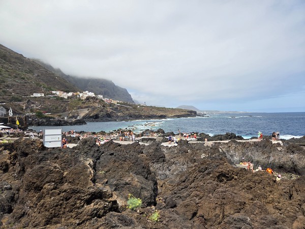 Charcos naturales de Garachico con plataformas sobre roca volcánica y bañistas disfrutando del entorno.