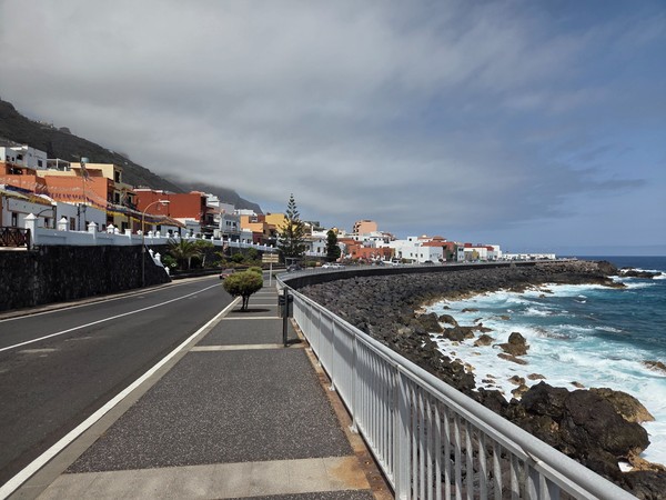 Tramo del paseo marítimo de Garachico con acera amplia, barandilla y casas de colores junto al mar bravo.