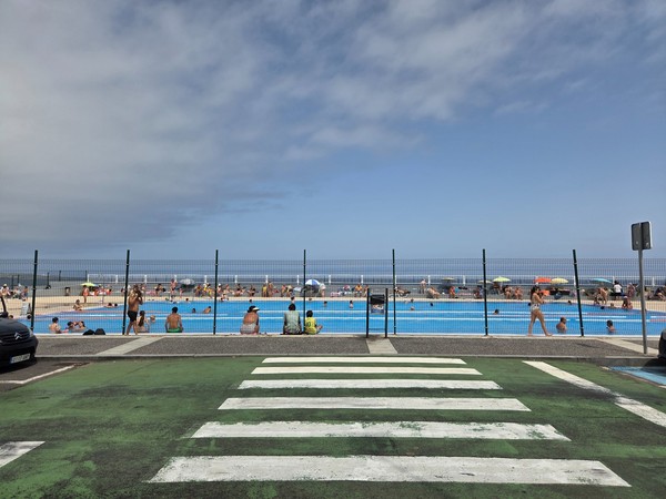 Piscina municipal de Garachico frente al océano con bañistas y sombrillas.