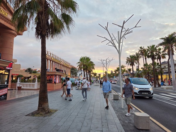 Paseo de la Milla de Oro con palmeras y peatones al atardecer frente al Hard Rock Café Tenerife.