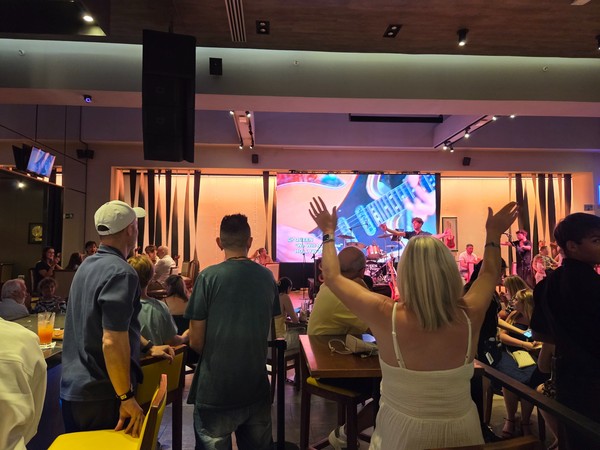 Sala interior del Hard Rock Café Tenerife con escenario, mesas y ambiente animado.