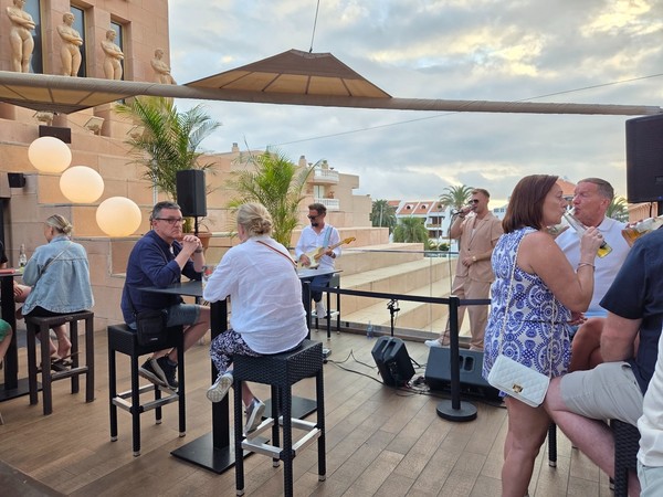 Clientes disfrutando de bebidas y música en la terraza superior del Hard Rock Café Tenerife con músicos en directo.