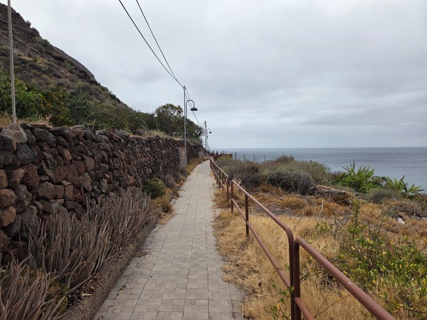 Andén peatonal hacia el litoral con farolas y vistas al océano.