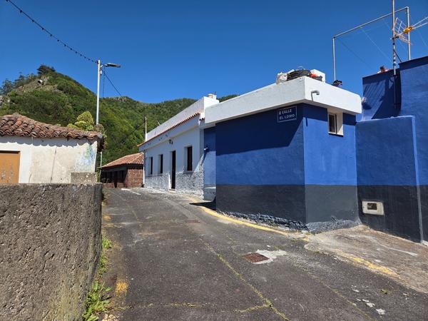 Calle El Lomo con su característica fachada azul cobalto y fondo montañoso.