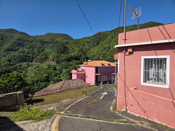 Conjunto de viviendas rosadas que se asoman sobre las montañas de Anaga.