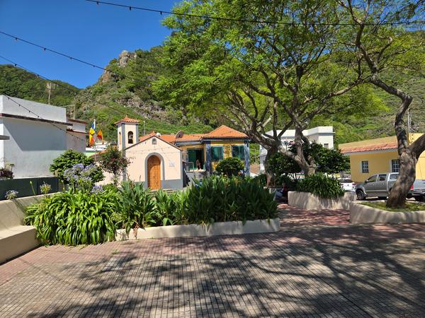 La pequeña ermita y la plaza central de Las Carboneras, rodeadas de árboles y casas de colores.
