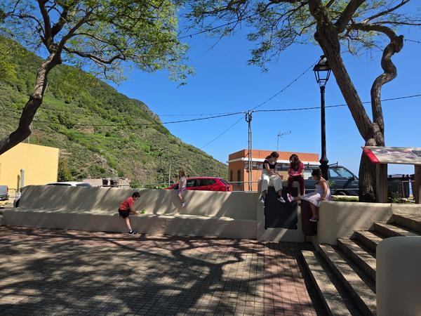 Niños jugando en la plaza sombreada de Las Carboneras en una tarde soleada.