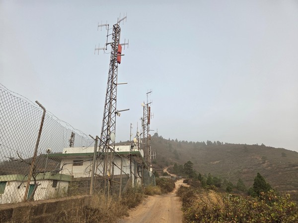 Conjunto de antenas y repetidores junto a la pista de acceso, cercado y con torres metálicas.
