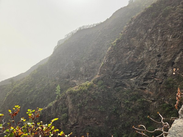 Laderas escarpadas con la traza del sendero a media montaña y vegetación de monteverde.