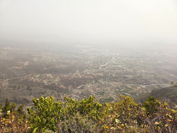 Vista del valle de Güímar desde la ladera en un día de calima, con los pueblos y bancales a lo lejos.