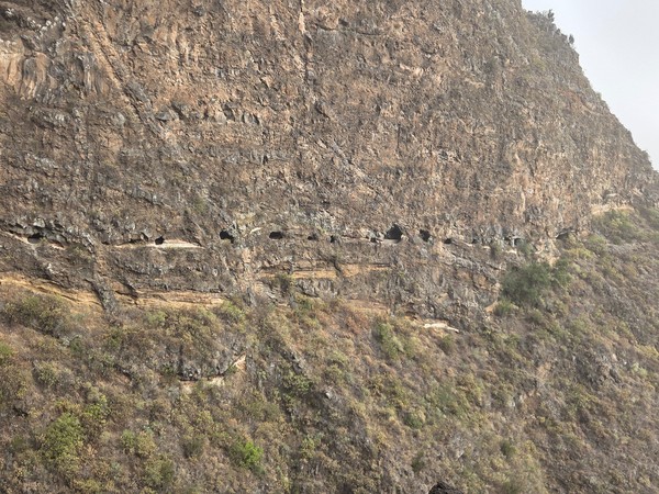 Franja de túneles con pequeñas 'ventanas' alineadas en la pared rocosa de la montaña.