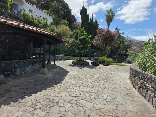 Plazoleta y zona cubierta de los antiguos lavaderos rodeada de jardines.