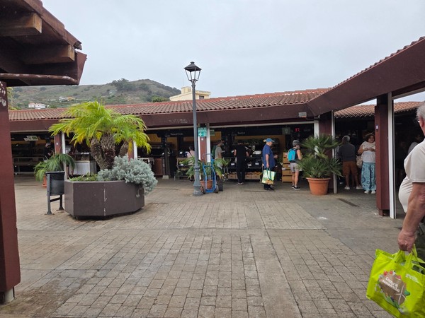 Patio central del Mercadillo de Tegueste con puestos y compradores en una mañana nublada.