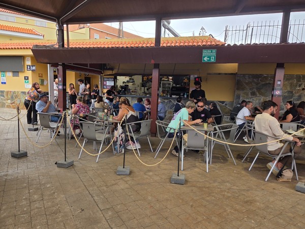 Terraza de la cafetería del mercadillo con clientes sentados y mostrador de atención.