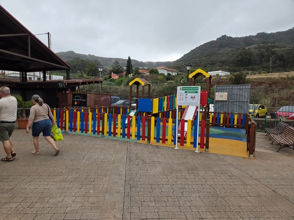 Parque infantil vallado y colorido dentro del mercadillo con tobogán.