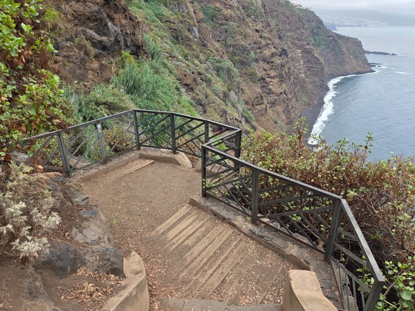 Plataforma de madera con barandillas metálicas en aspa que sirve de mirador sobre la costa.