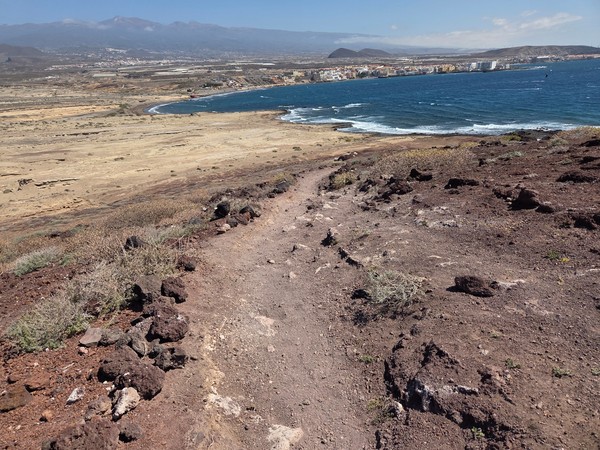Tramo del camino sobre la ladera de Montaña Bocinegro con El Médano y la costa extendiéndose al fondo.
