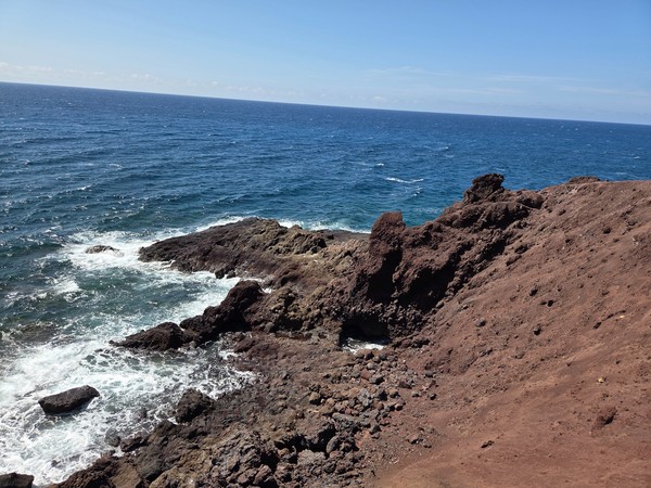 Risco volcánico y espuma del mar rompiendo en la base de Montaña Bocinegro.