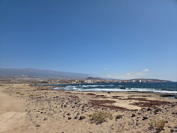Vista amplia de El Médano desde la zona de Montaña Bocinegro, con el litoral al fondo y mar de tonalidad azul.