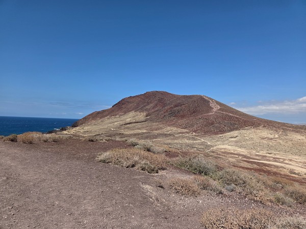 Perfil de Montaña Roja visto desde Montaña Bocinegro, con senderos marcados sobre laderas rojizas.