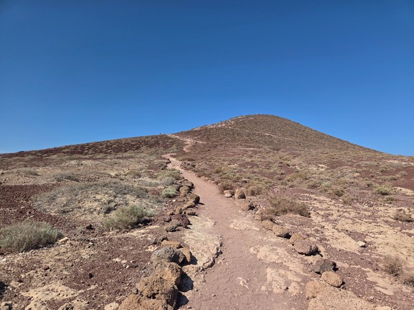 Senda de tierra y rocas ascendiendo por la ladera de Montaña Roja.