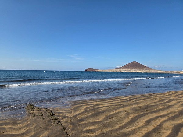 Montaña Roja vista desde la orilla de la playa con olas suaves.