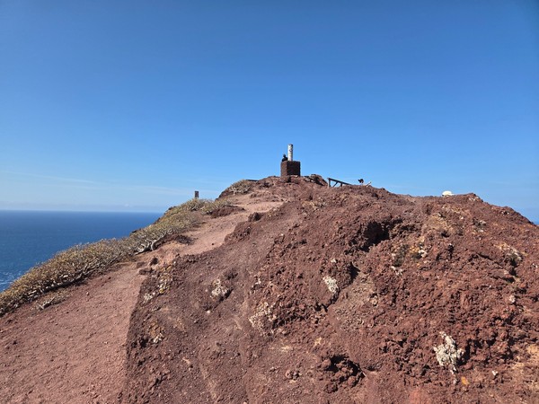 Cima de Montaña Roja con hito geodésico y vistas al océano.