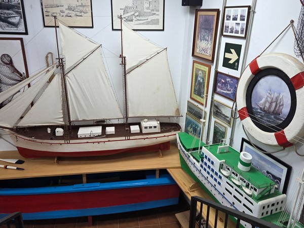 Dos grandes veleros de madera con banderas europeas exhibidos tras cristal.