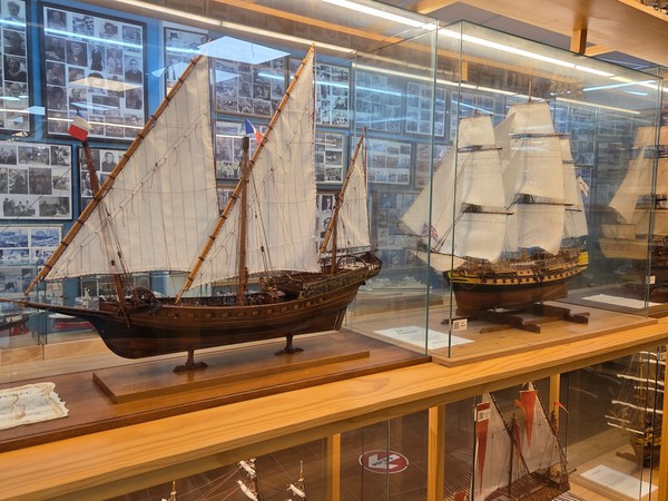 Pasillo del museo con diplomas, placas y varias maquetas de barcos de vela.