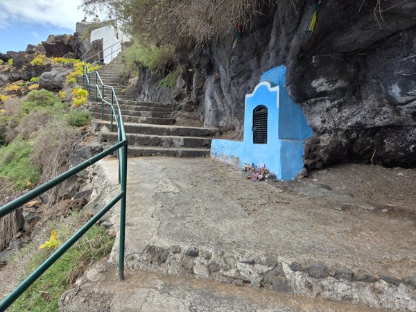 Pequeño altar azulado de la Virgen del Carmen excavado en la roca junto a la escalera del acantilado