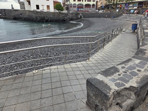 Rampa peatonal con barandilla de acero inoxidable que conecta el paseo con la Playa del Muelle.