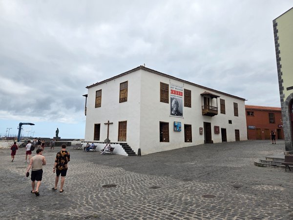Fachada principal de la Casa de la Real Aduana con balcones de madera y cruz de piedra.