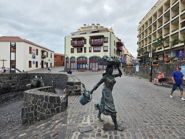 Escultura de bronce que representa a una vendedora de pescado con cesta sobre la cabeza en la plaza del Muelle.